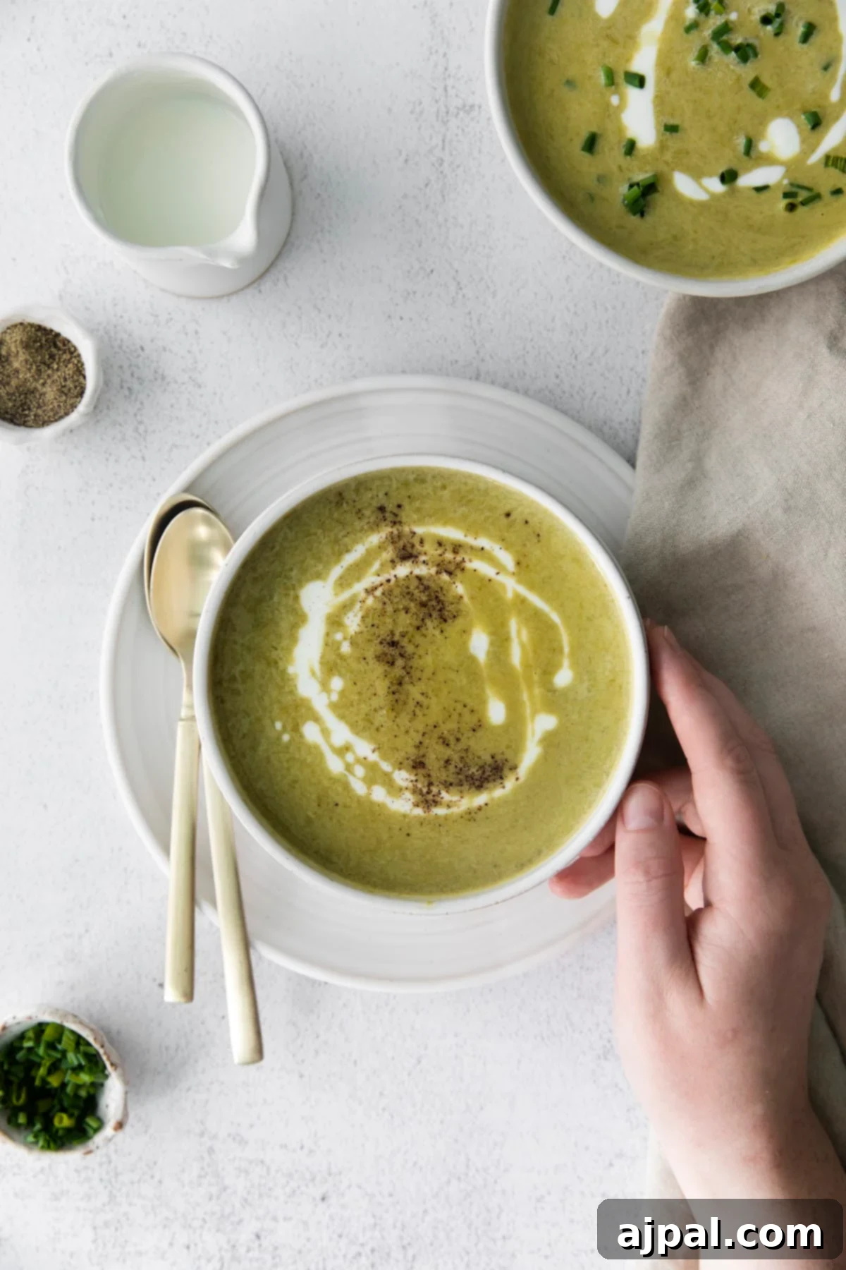 Velvety Instant Pot Asparagus Soup 2 creamy asparagus soup in a white bowl with a swirl of cream and chopped chives on top and lots of fresh cracked pepper
