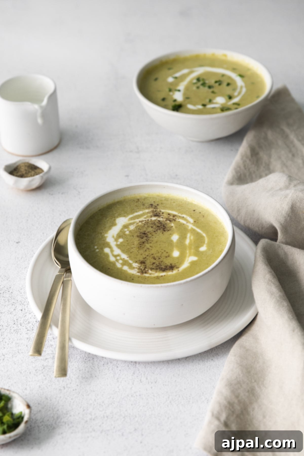 Velvety Instant Pot Asparagus Soup 10 creamy asparagus soup in a white bowl with a swirl of cream on top and lots of fresh cracked pepper