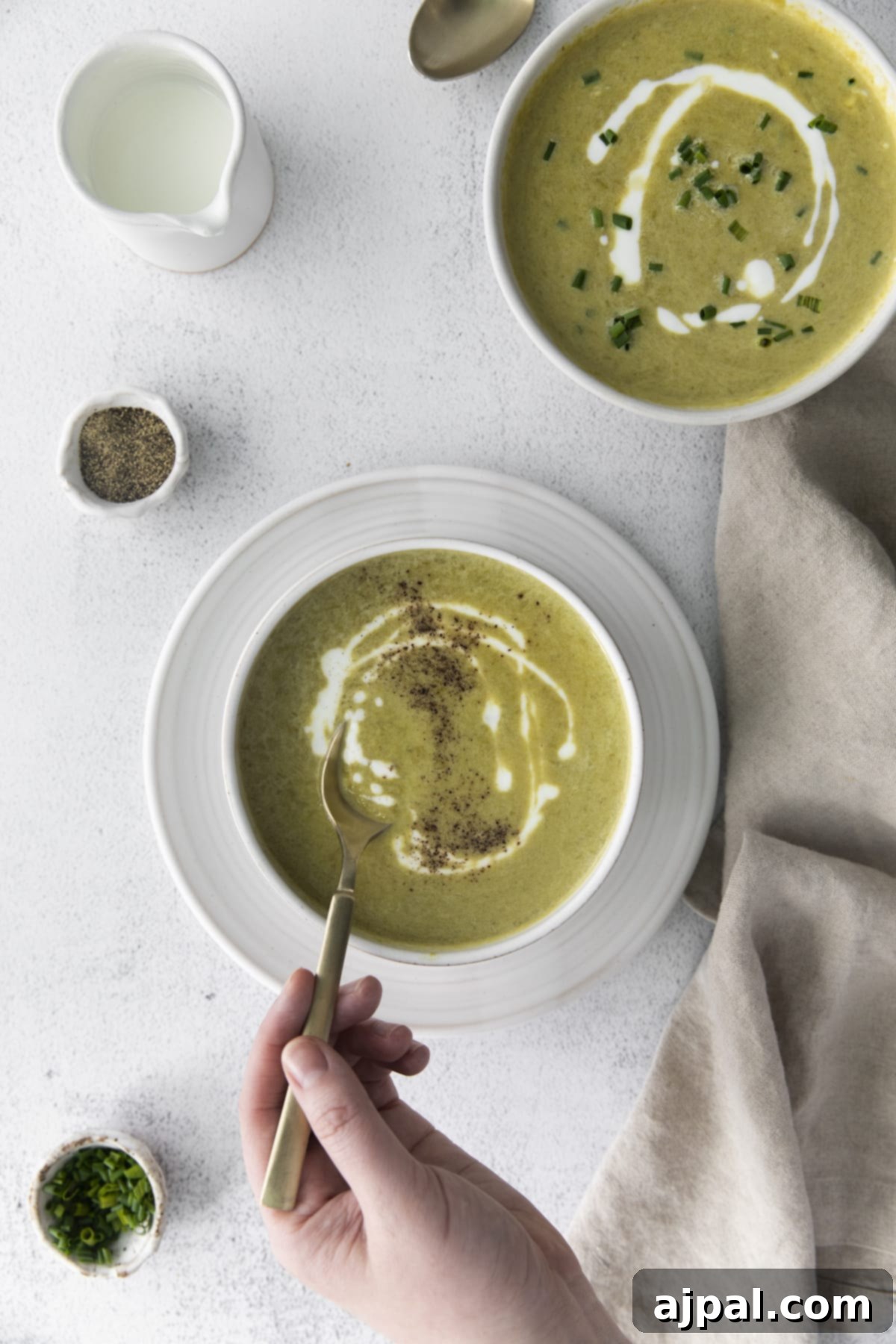 Velvety Instant Pot Asparagus Soup 9 creamy asparagus soup in a white bowl with a swirl of cream on top and lots of fresh cracked pepper