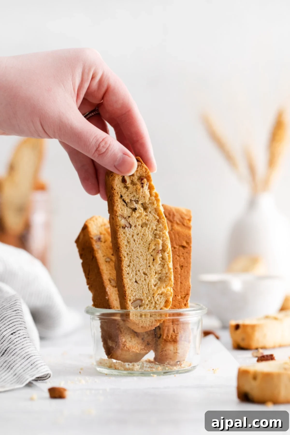 Artisan Maple Pecan Biscotti 2 A hand grabbing a baked biscotti with pecan from a jar on a table