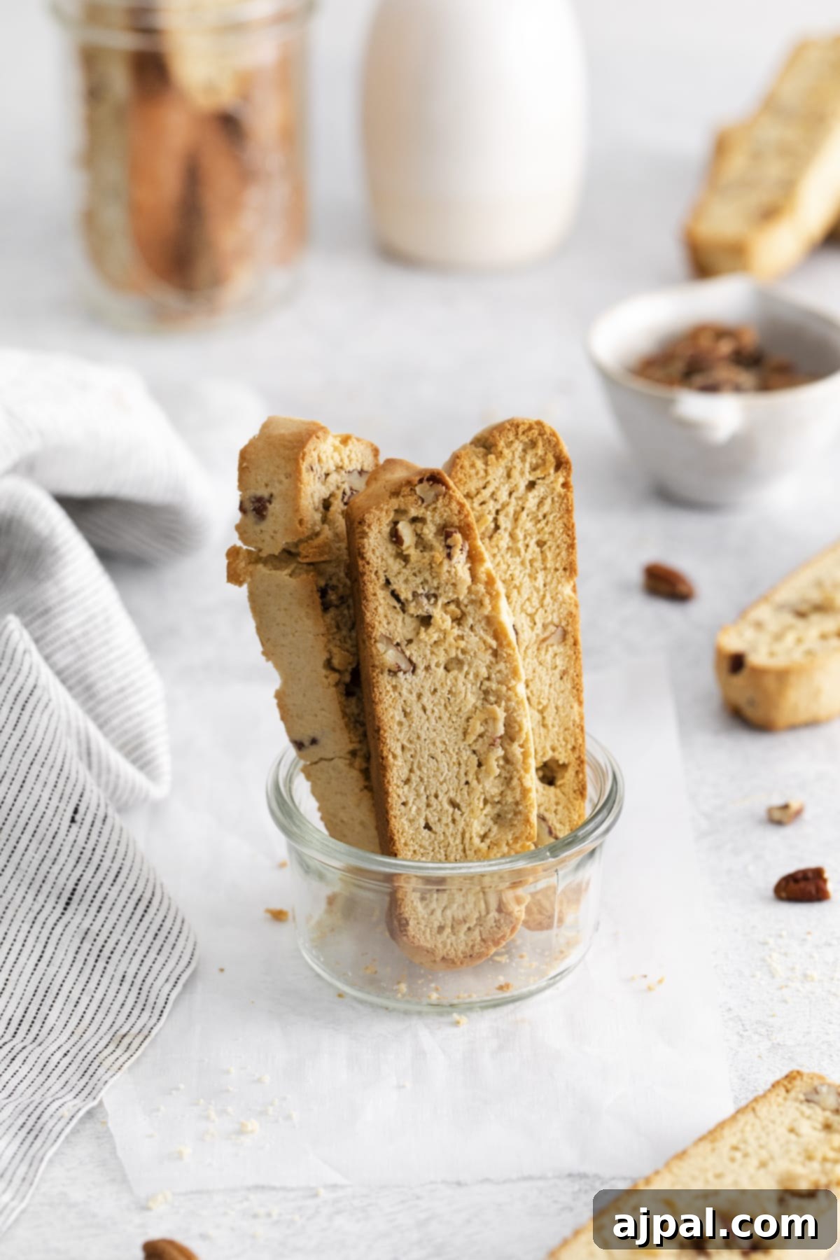 Golden Maple Pecan Biscotti 12 A close-up shot of a glass bowl filled with perfectly baked maple pecan biscotti pieces, showcasing their golden brown crust and pecan chunks.