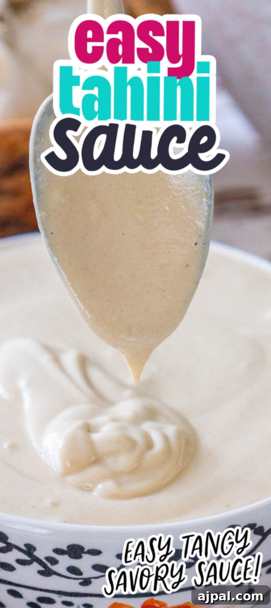 A spoon delicately lifts creamy tahini sauce over a bowl, illustrating its perfect, smooth consistency on a rustic wooden surface.