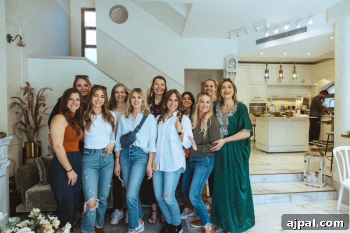 A group of women happily gathered in a living room, engaged in a casual discussion about their easy tahini sauce recipe, sharing culinary secrets and laughter.