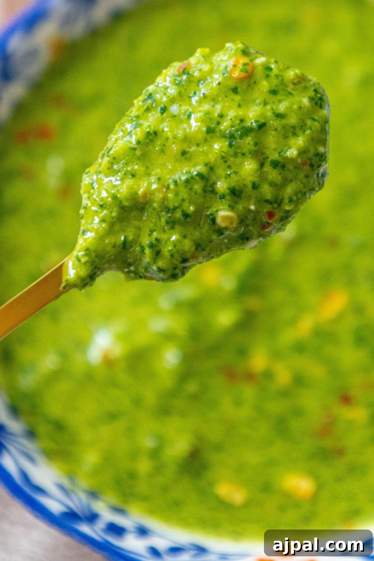 Skhug Zhoug Sauce Recipe 21 Bright green zhoug sauce with delicate flecks of cilantro and vibrant red pepper flakes, artfully presented in a decorative blue mug, ready for another delicious and flavorful meal.