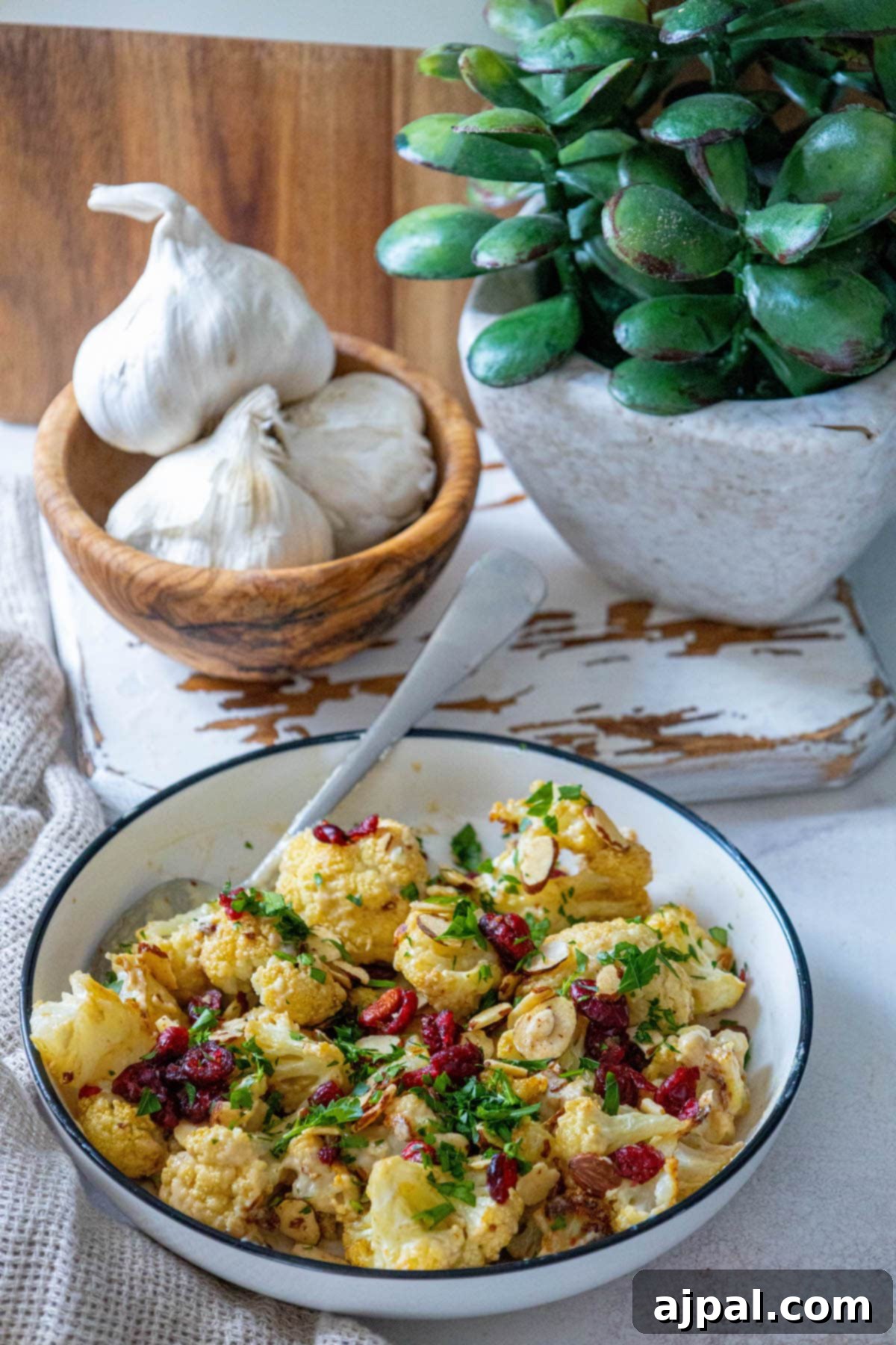 A vibrant bowl of tahini roasted cauliflower, adorned with bright cranberries and fresh garlic, ready to be enjoyed as a flavorful and healthy meal.
