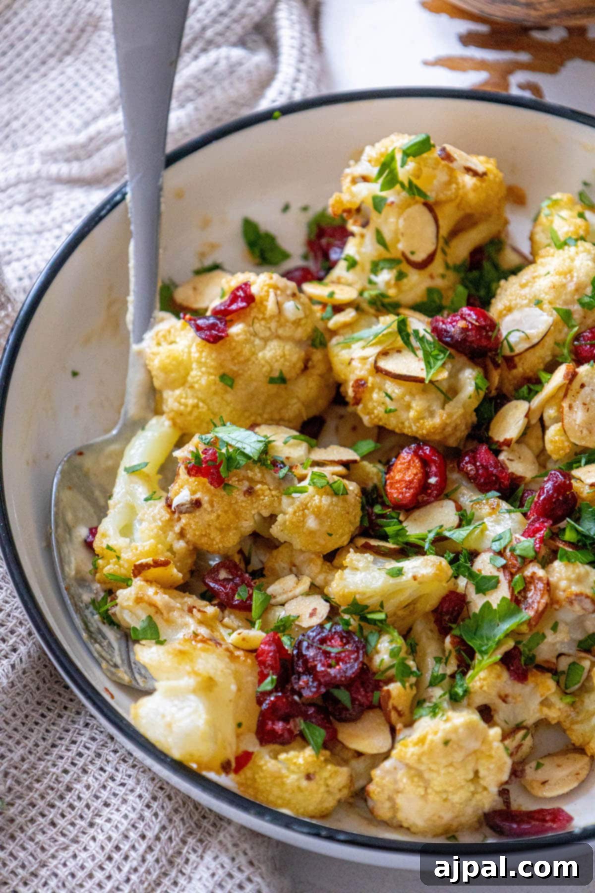 A beautifully presented cauliflower bowl featuring tahini roasted cauliflower, adorned with vibrant cranberries and crunchy almonds.
