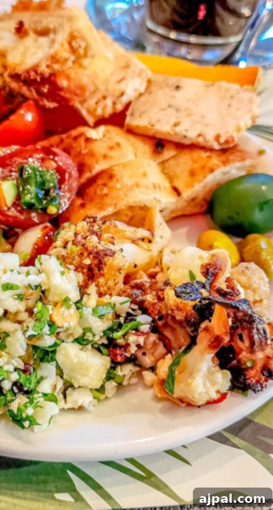 A close-up of a plate showcasing perfectly cooked tahini roasted cauliflower, generously topped with toasted almonds.