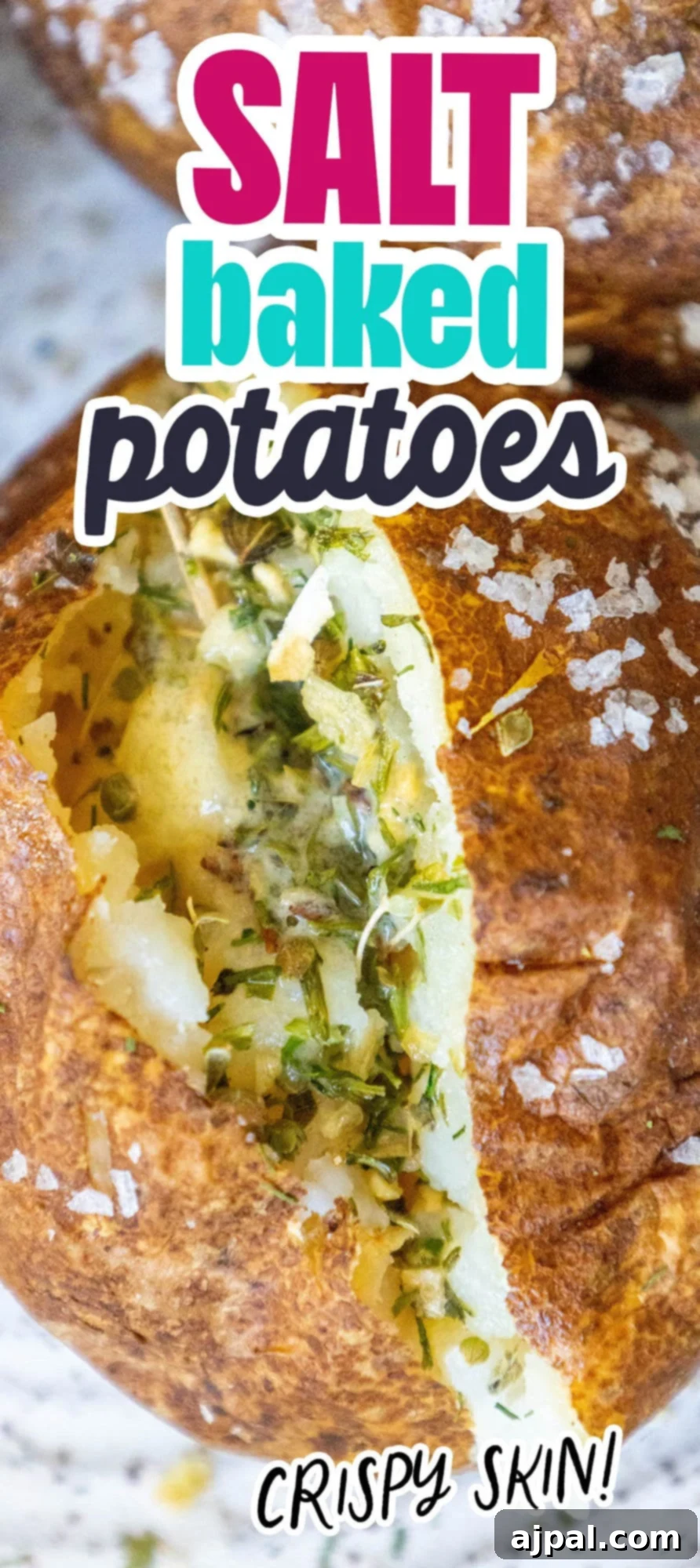 baked potato covered in flaky sea salt cut in half with butter in the middle and herb seasoning inside on a speckled plate with two other salt baked potatoes on the plate next to it
