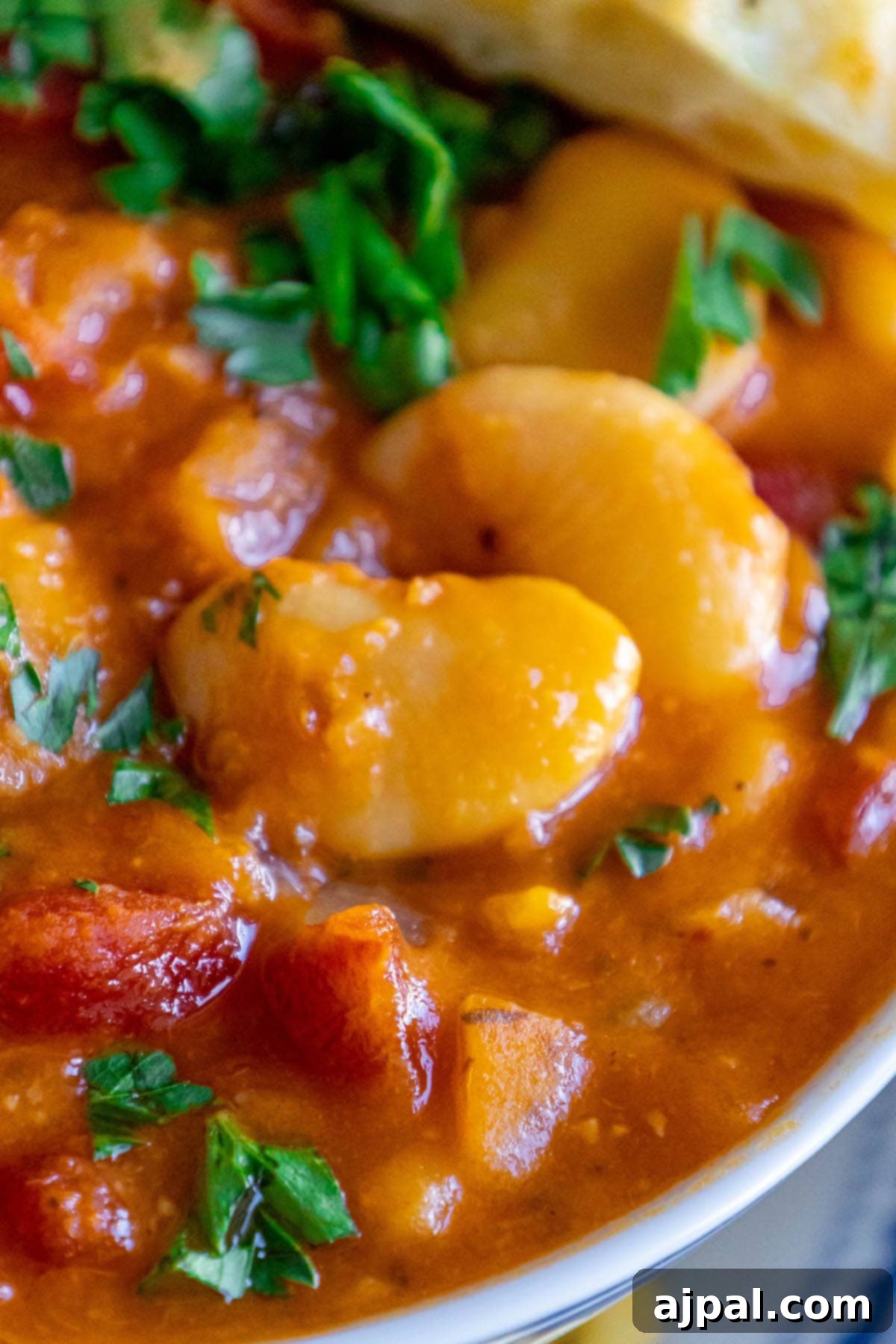 baked greek beans in a tomato sauce with chopped herbs and giant white beans