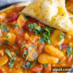 baked greek beans in a tomato sauce with chopped herbs and giant white beans