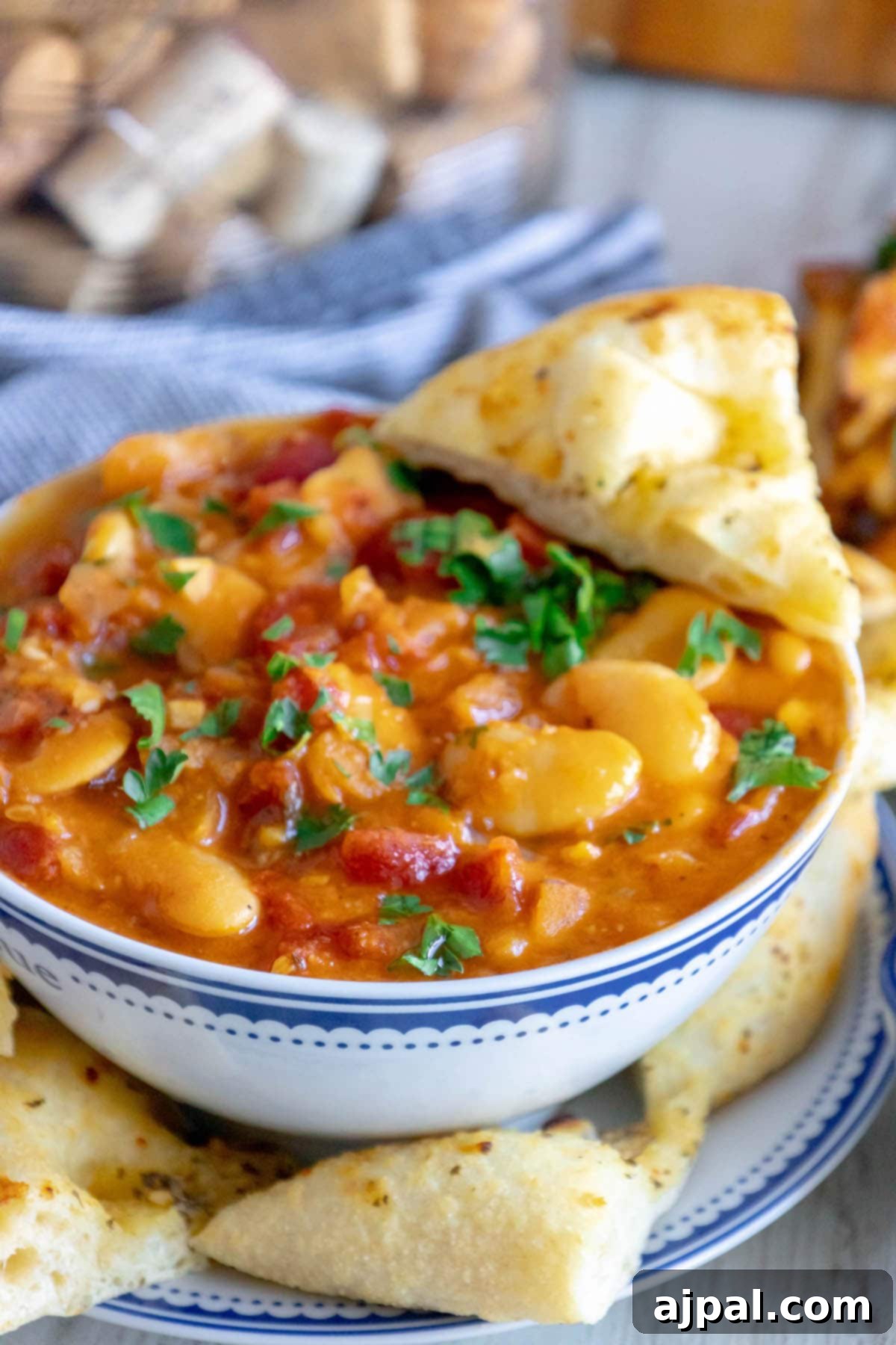 baked greek beans in a tomato sauce with chopped herbs and giant white beans