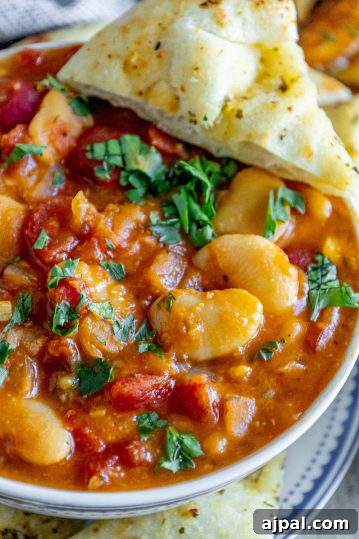 baked greek beans in a tomato sauce with chopped herbs and giant white beans
