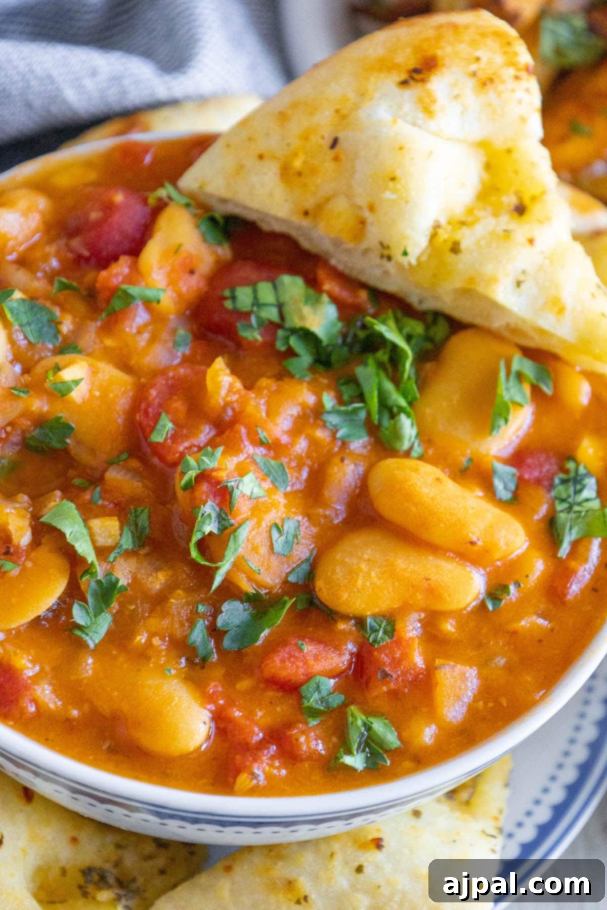 baked greek beans in a tomato sauce with chopped herbs and giant white beans