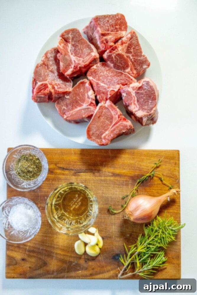 raw lamb chops on a white plate next to a cup of wine, herbs on a table, salt, a shallot, and fresh cracked pepper