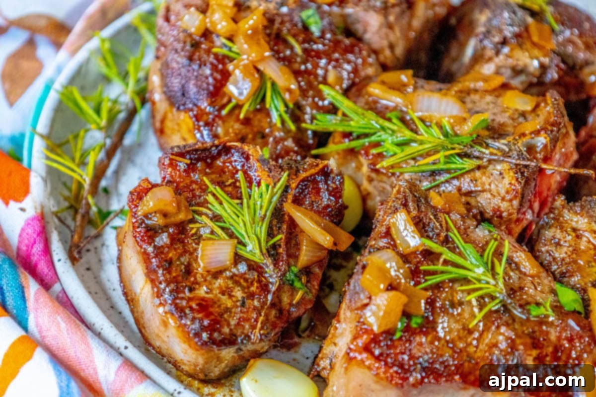 seared lamb chop on a white plate with a sprig of rosemary and sea salt flakes on top 