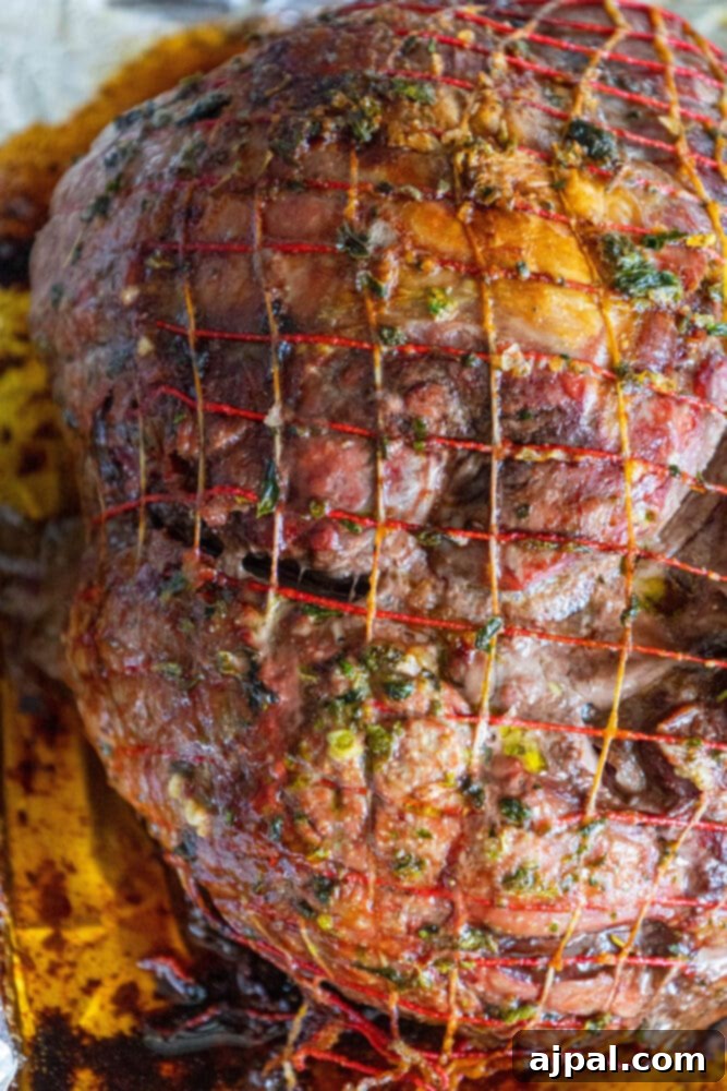 The Ultimate Easy Roasted Leg of Lamb 7 A perfectly prepared raw leg of lamb, coated in a savory herb rub, resting in a foil-lined baking tray, ready for roasting to achieve a tender and juicy result.