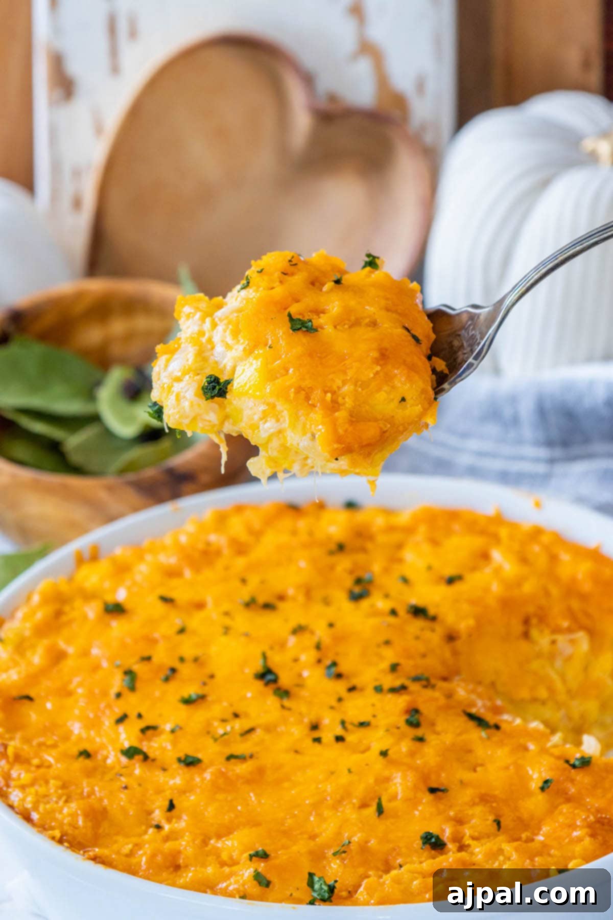 Savory Roasted Squash Gratin 2 A vibrant cheesy squash casserole baked in a pristine white dish, elegantly topped with golden Cheez-It crackers, melted cheddar cheese, and a sprinkle of fresh chopped parsley for garnish.