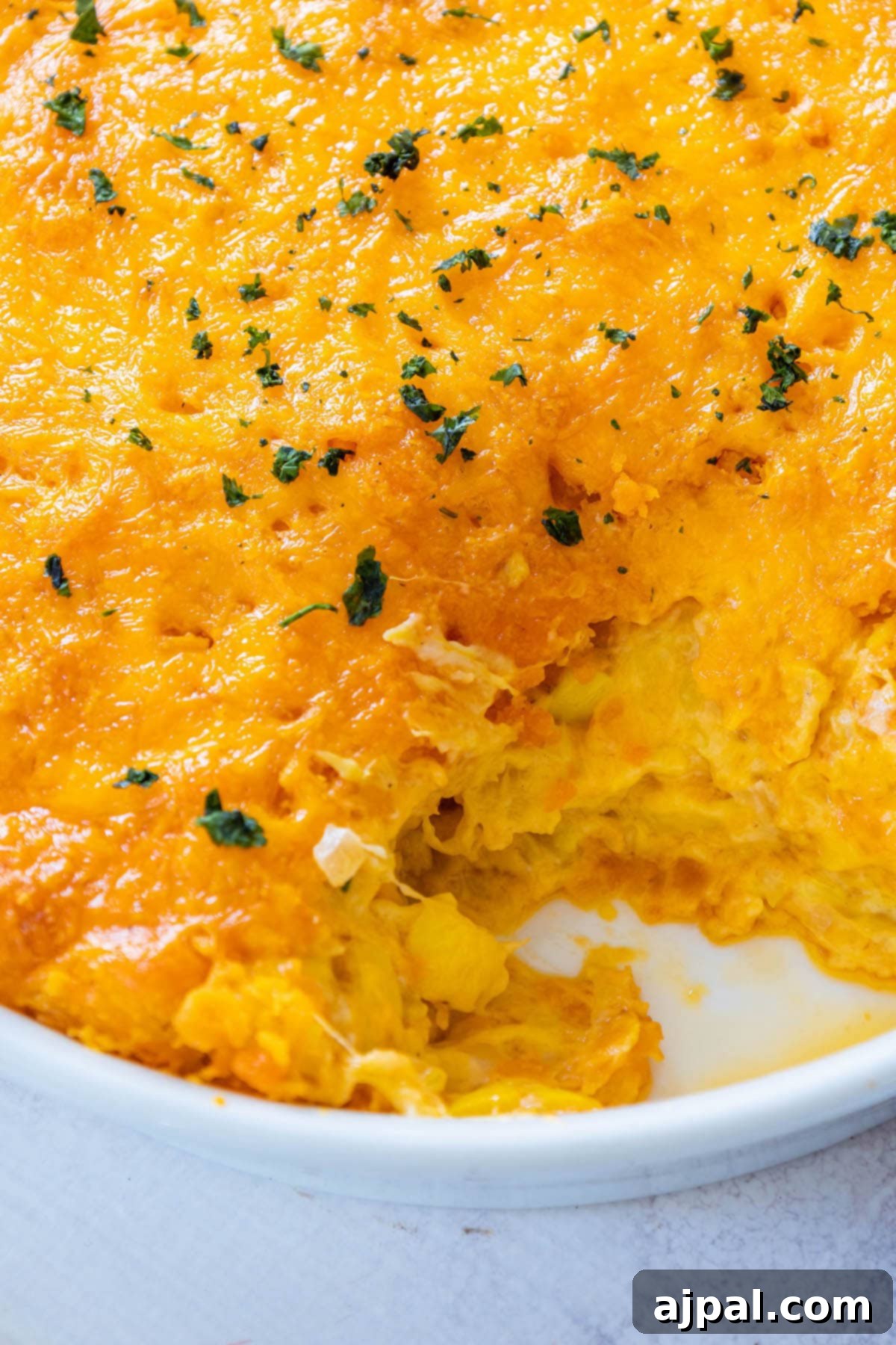 Savory Roasted Squash Gratin 7 A cheesy squash casserole with a section scooped out, revealing the tender, baked squash and creamy interior beneath a crisp cracker topping.