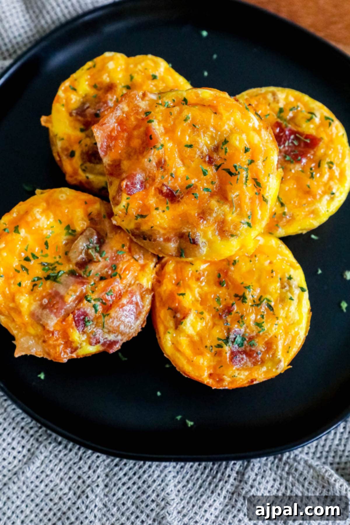 Hashbrown Egg Nests 8 Egg cups with bacon and hashbrown stacked on top of each other on a black plate, ready to be enjoyed