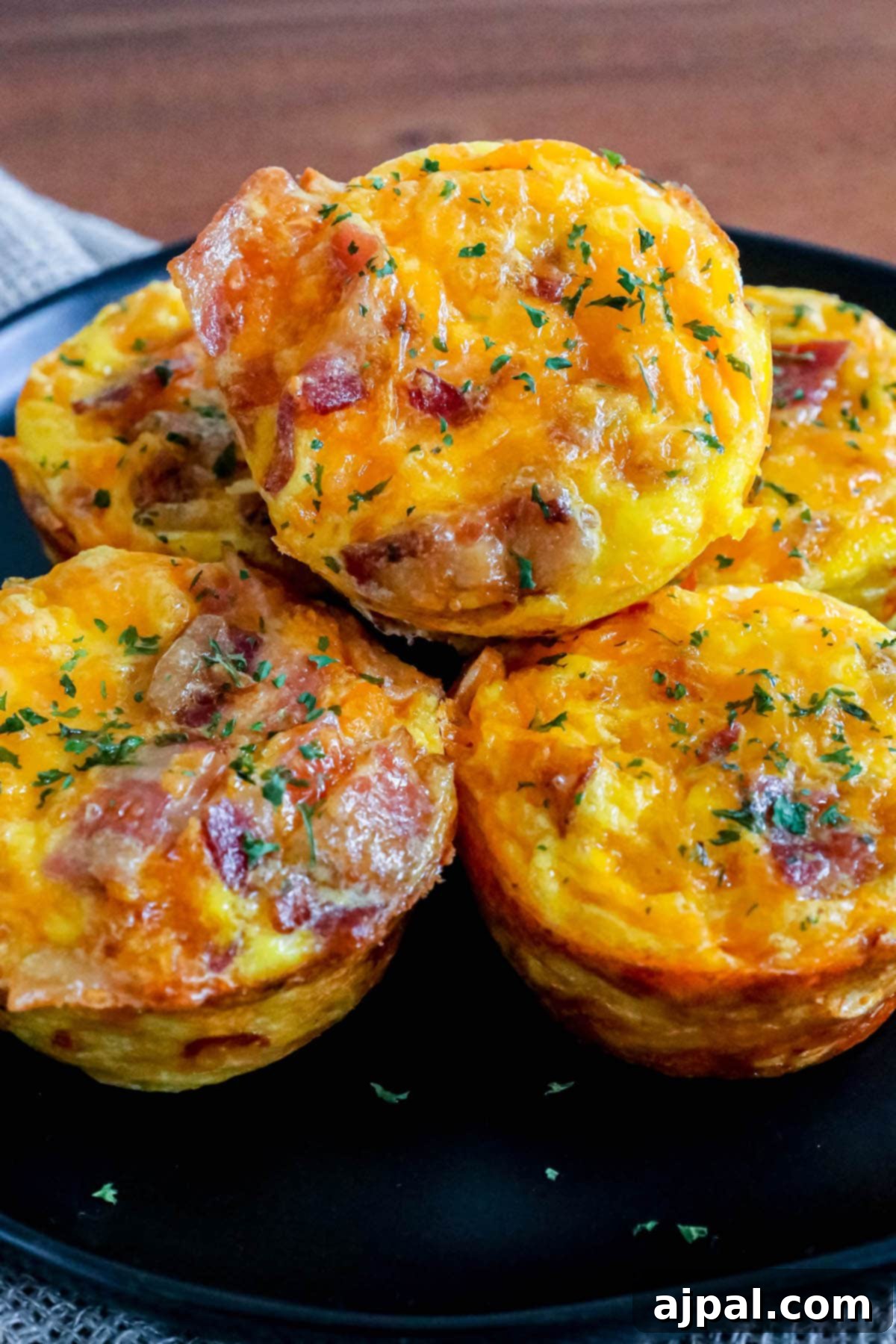 Hashbrown Egg Nests 9 Egg cups with bacon and hashbrown stacked on top of each other on a black plate, artfully arranged
