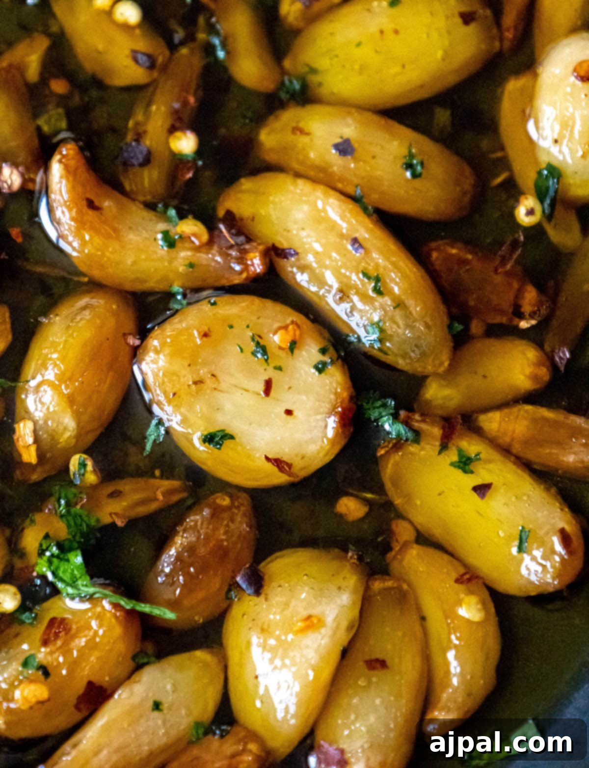 Garlic Gold 9 A pan with onions and herbs sautéed in the best garlic confit recipe, showcasing a flavorful cooking application.