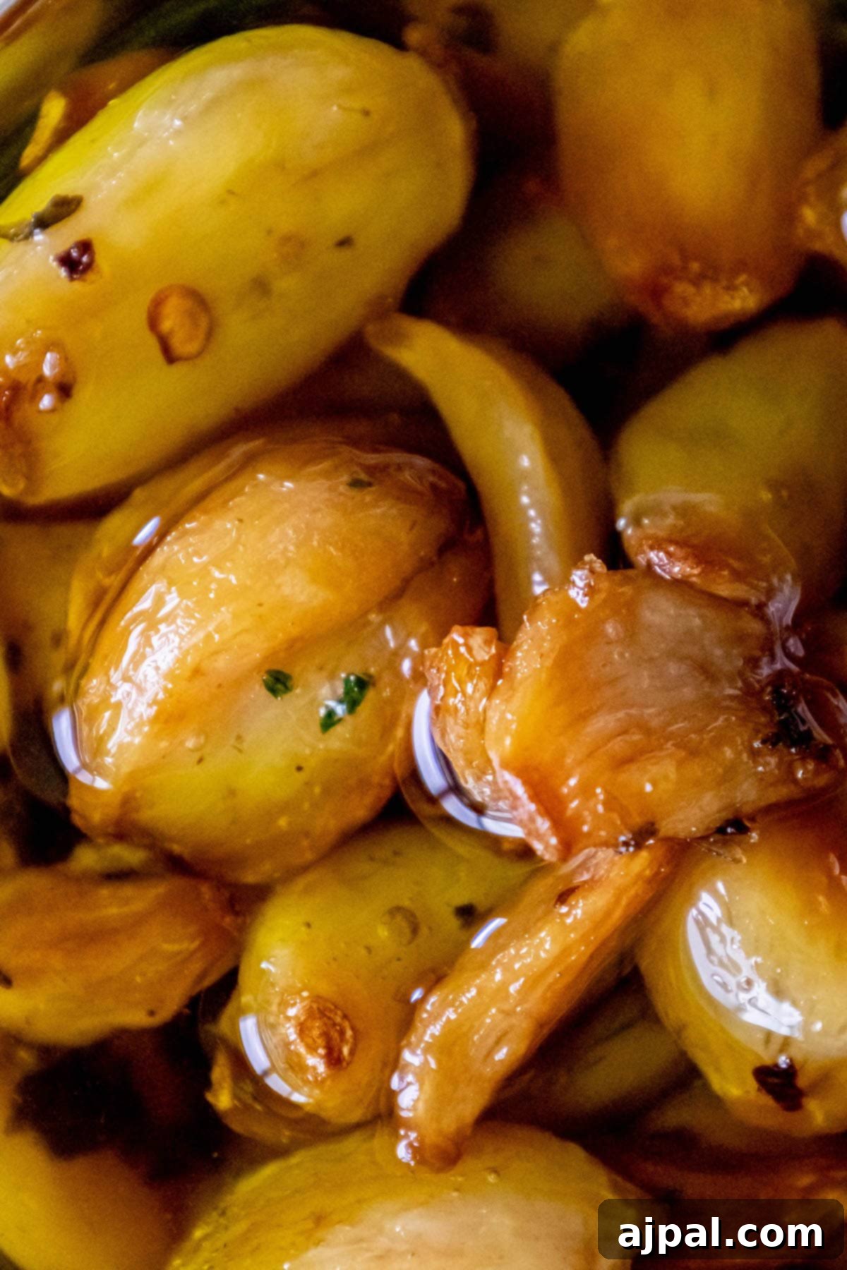 Garlic Gold 4 A close-up of dark brown garlic confit in olive oil in a clear glass dish, highlighting its rich color and inviting texture.