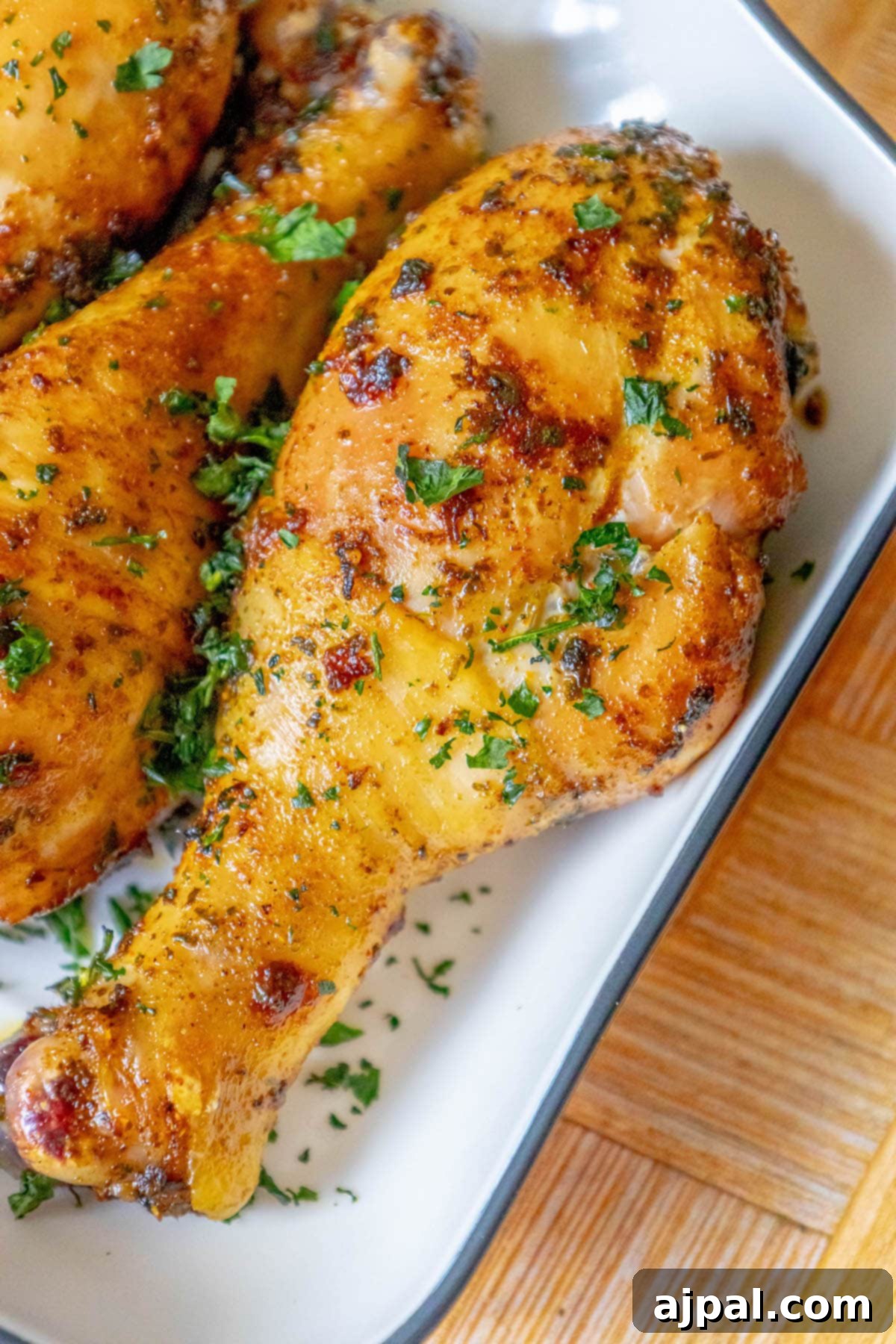 Tender Confit Chicken Legs 2 chicken confit drumsticks topped with parsley in a white dish