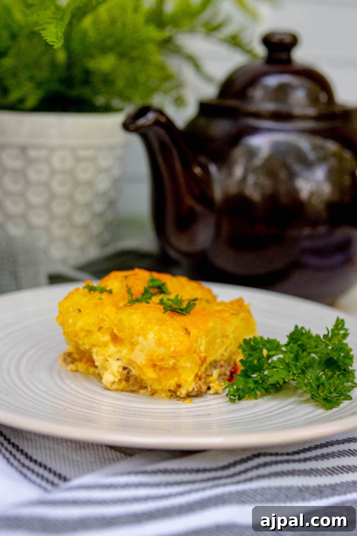 Hearty Tater Tot Breakfast Bake 3 A hearty and cheesy tater tot breakfast casserole portioned on a white plate, ready to be enjoyed.