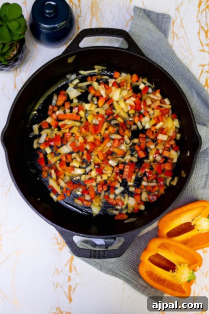 Hearty Tater Tot Breakfast Bake 8 Chopped onions and bell peppers sautéing in a hot pan, becoming tender and fragrant.