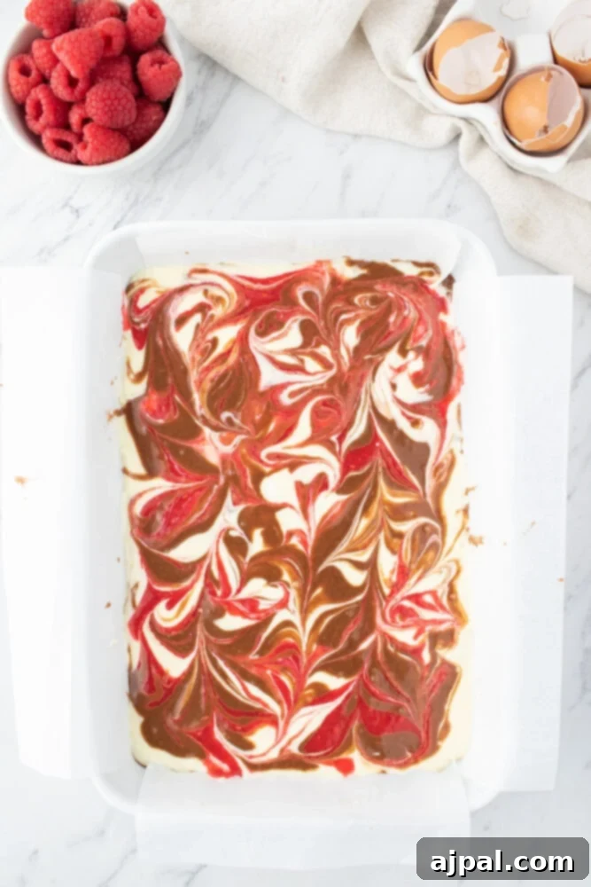 Ultimate Raspberry Cheesecake Brownies 13 marbled brownie batter in a glass baking dish