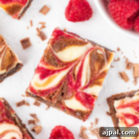 Ultimate Raspberry Cheesecake Brownies 18 Swirled raspberry cheesecake brownies on a white plate.
