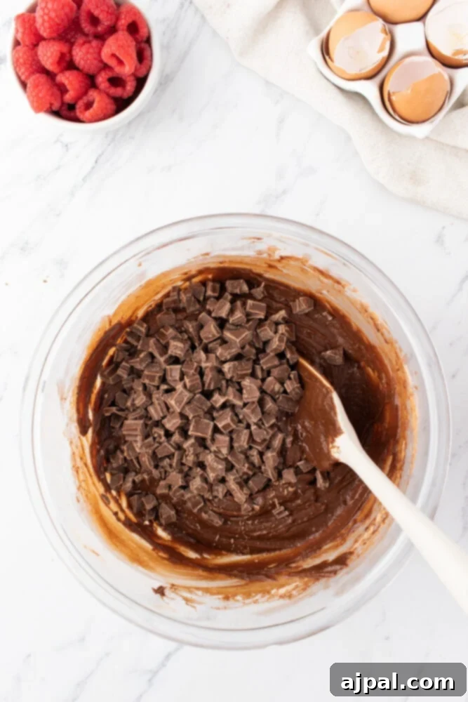Ultimate Raspberry Cheesecake Brownies 10 mixing chocolate chips into brownie batter in a bowl