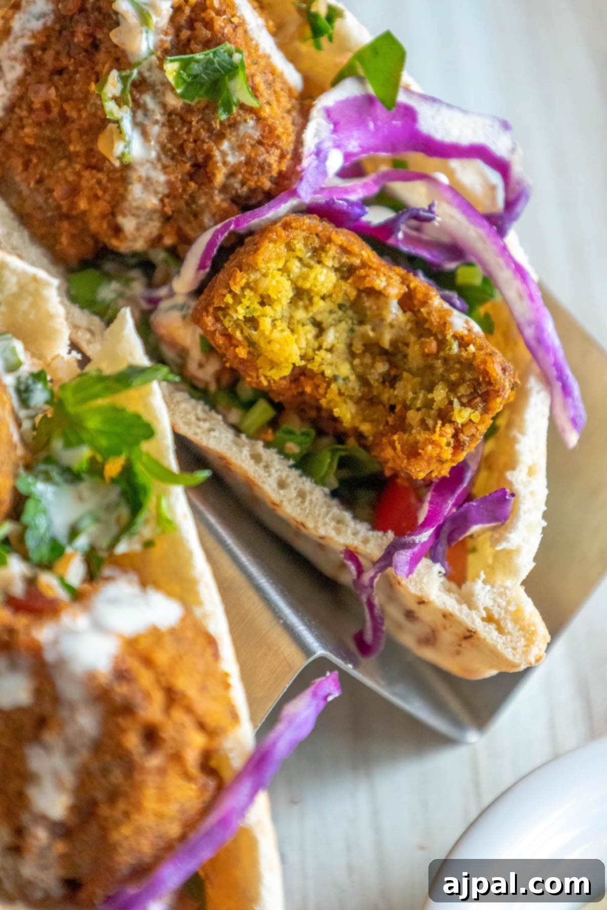 pita stuffed with falafel balls, cabbage, and salad with tahini sauce ladled on top