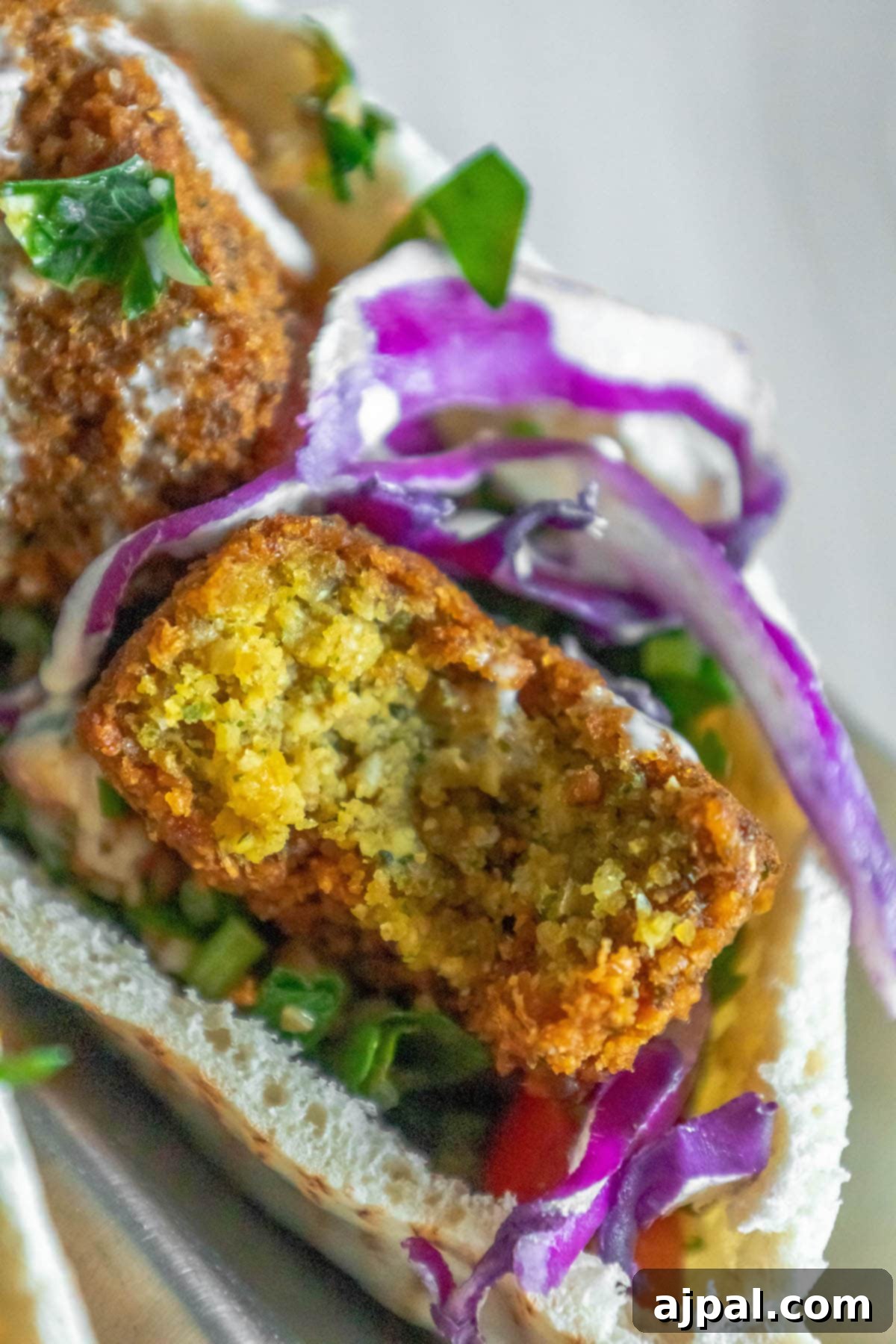 pitas stuffed with falafel balls, cabbage, and salad with tahini sauce ladled on top