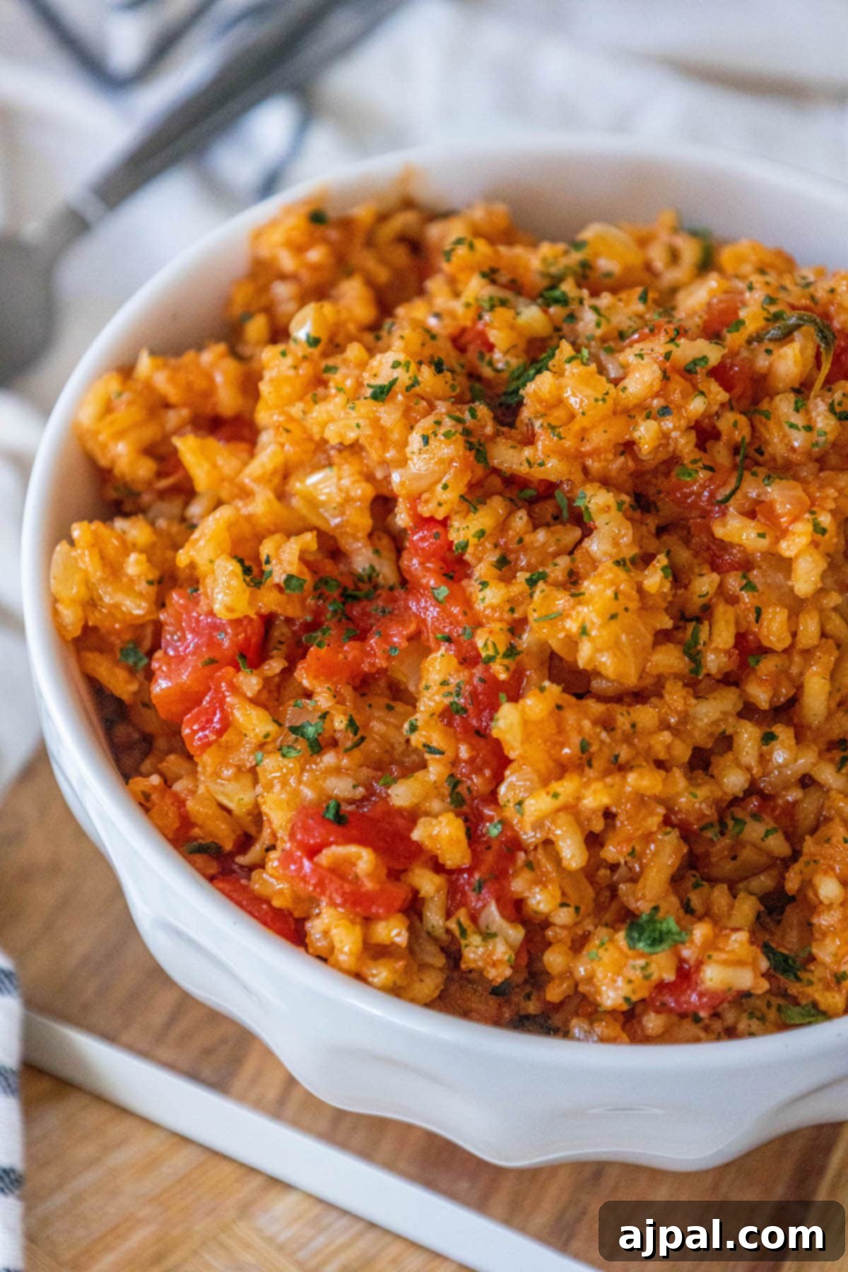 A rustic cutting board laden with easy Mexican rice, accompanied by fresh tomatoes, vibrant herbs, and a wooden serving spoon, ready for a delightful meal.