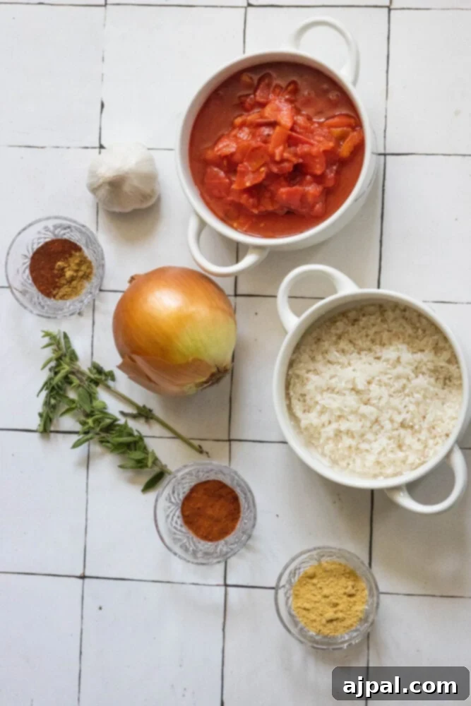A flat lay arrangement showcasing the essential ingredients for Mexican rice: diced tomatoes, chopped onion and garlic, a jalapeño, dry spices, and raw long-grain white rice, all neatly displayed on a wooden surface.