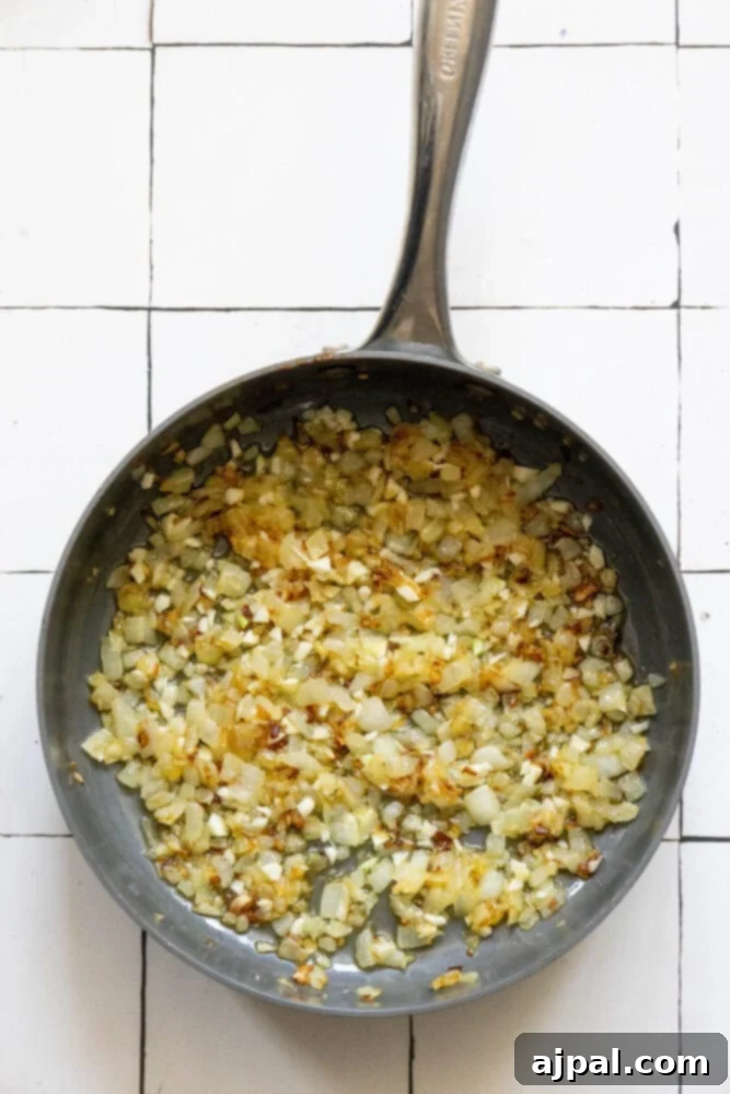Chopped onions and minced garlic gently browning in a large, hot skillet, releasing their fragrant aromas as they cook in oil.