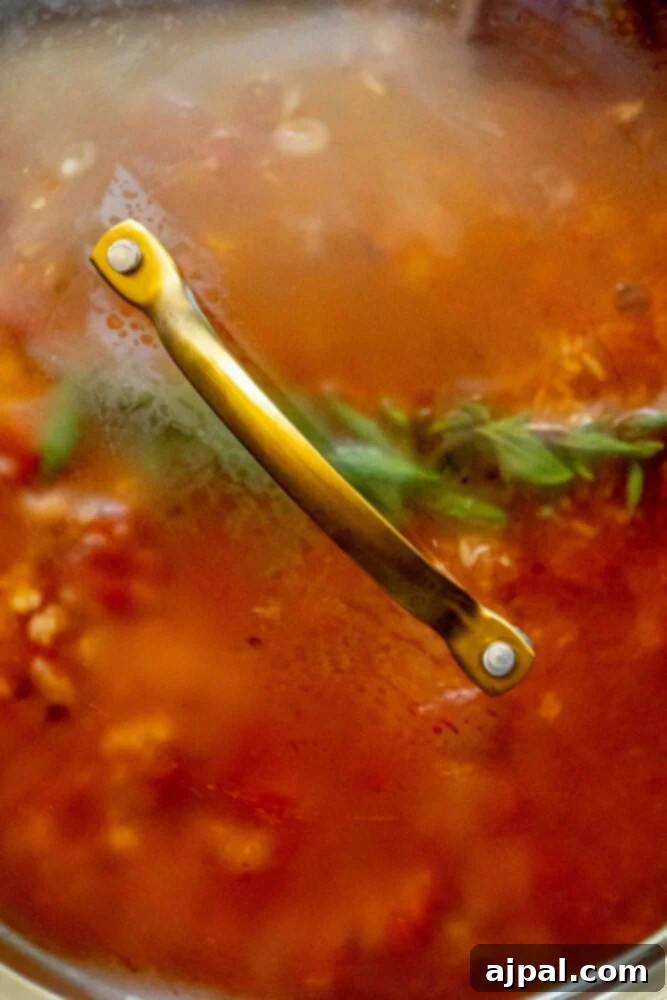 A pan with a tight-fitting lid, containing Mexican rice gently simmering, indicating it's in the final cooking stage.