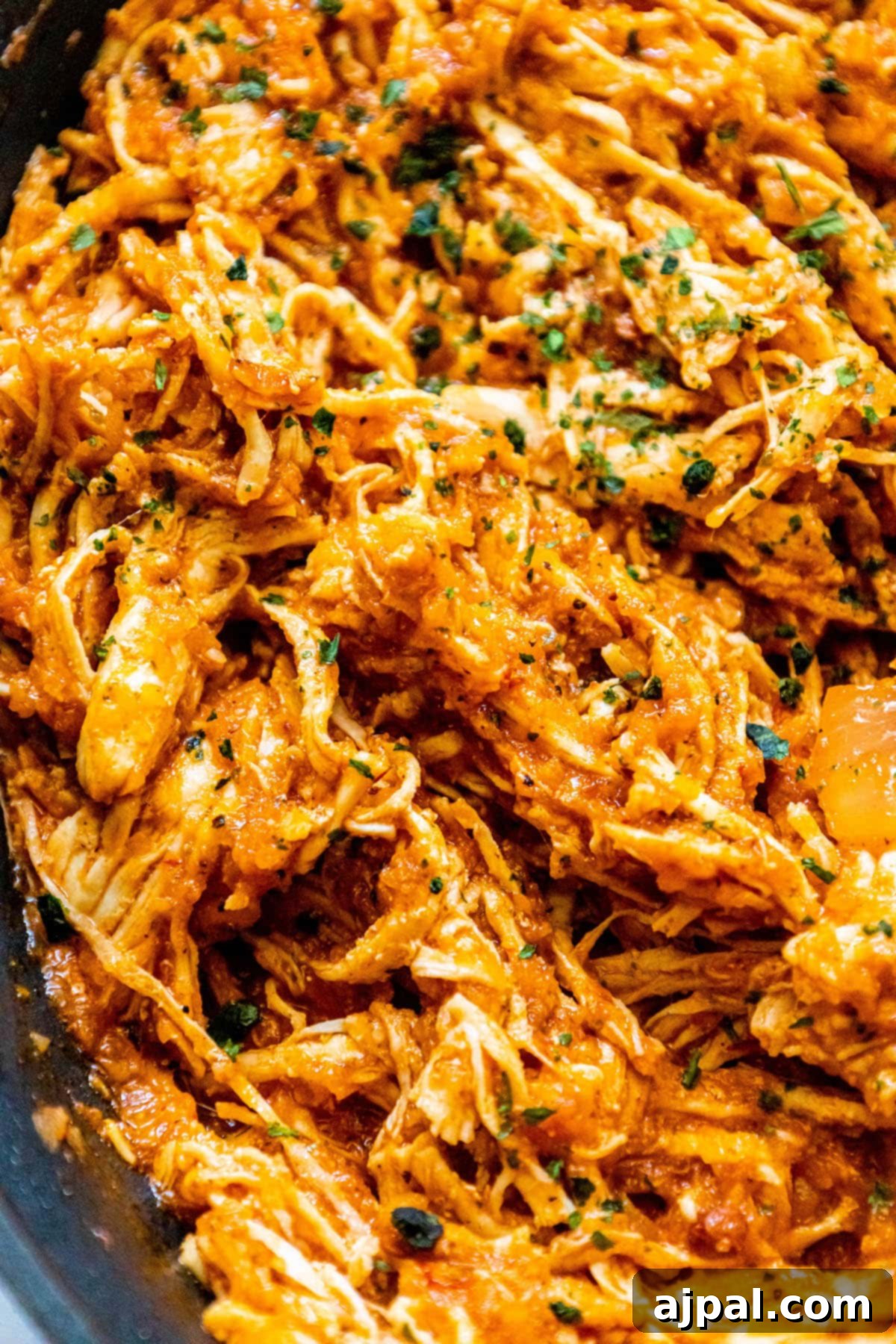 shredded chicken tinga in a pan with chopped cilantro on top
