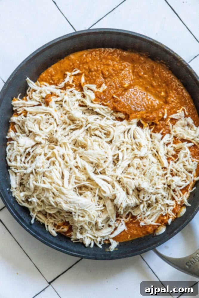 tinga sauce in a pan with shredded chicken poured on top 