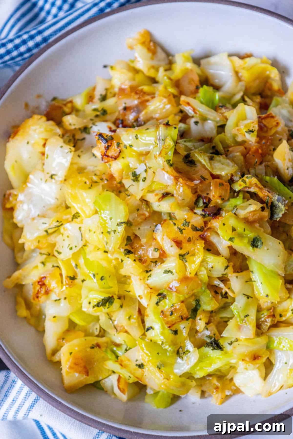 Caramelized Cabbage and Onions 3 A serving bowl filled with golden-brown fried keto cabbage, resting on a charming blue and white checkered cloth.