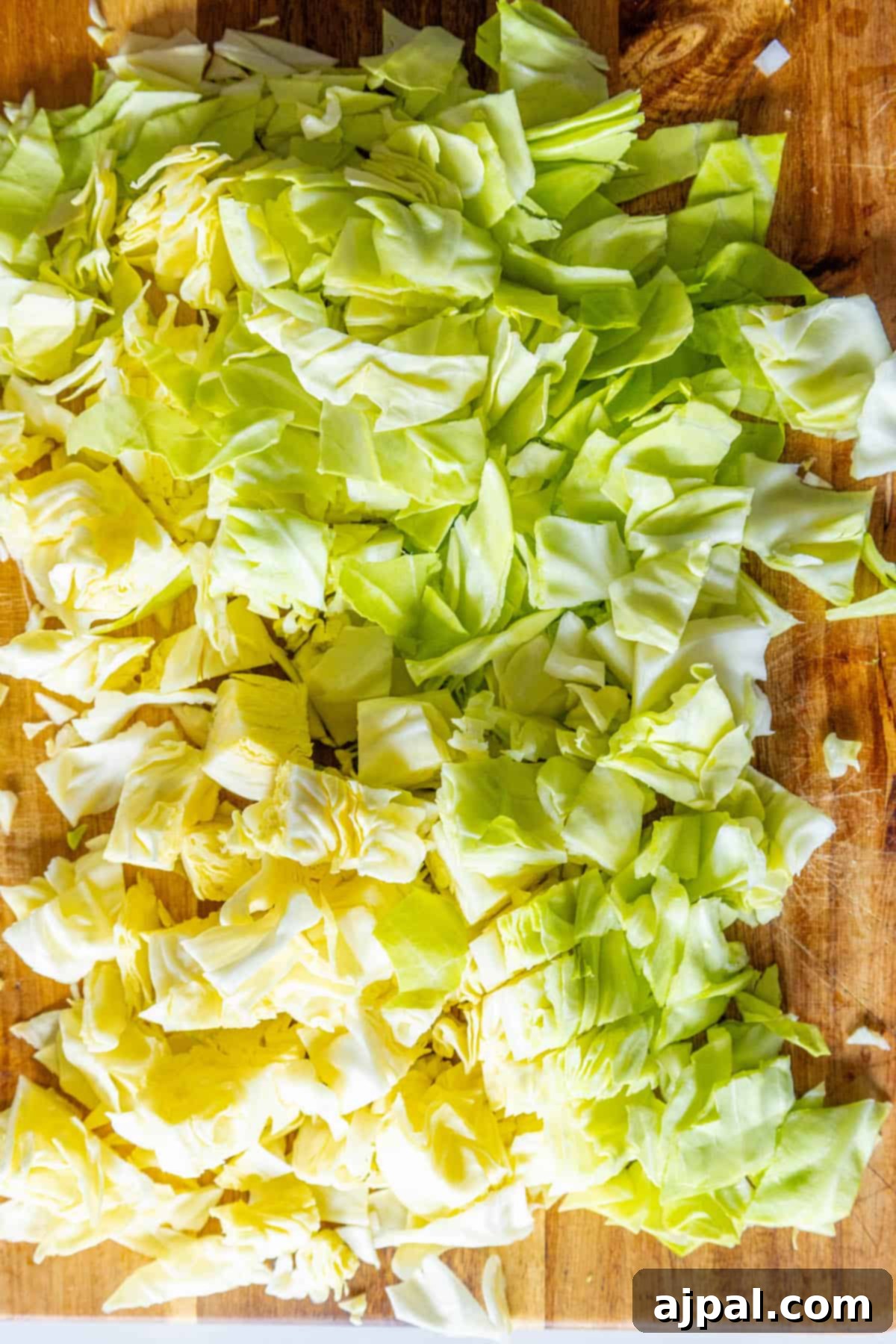 Caramelized Cabbage and Onions 6 Freshly shredded cabbage on a wooden cutting board, prepped for a delicious St. Patrick's Day recipe.