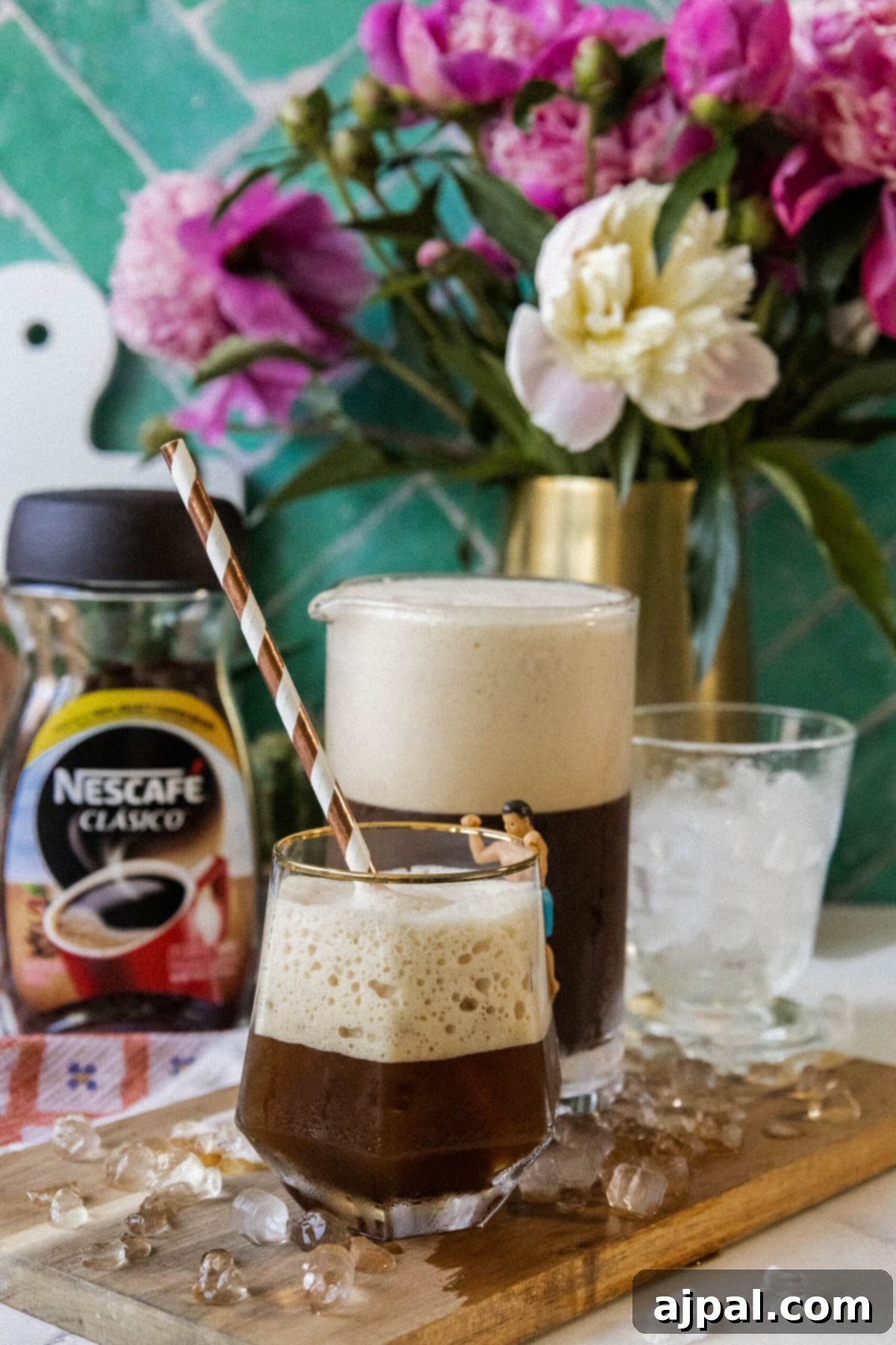 Whipped Greek frappé coffee in a glass with ice and foam and a paper straw on a table