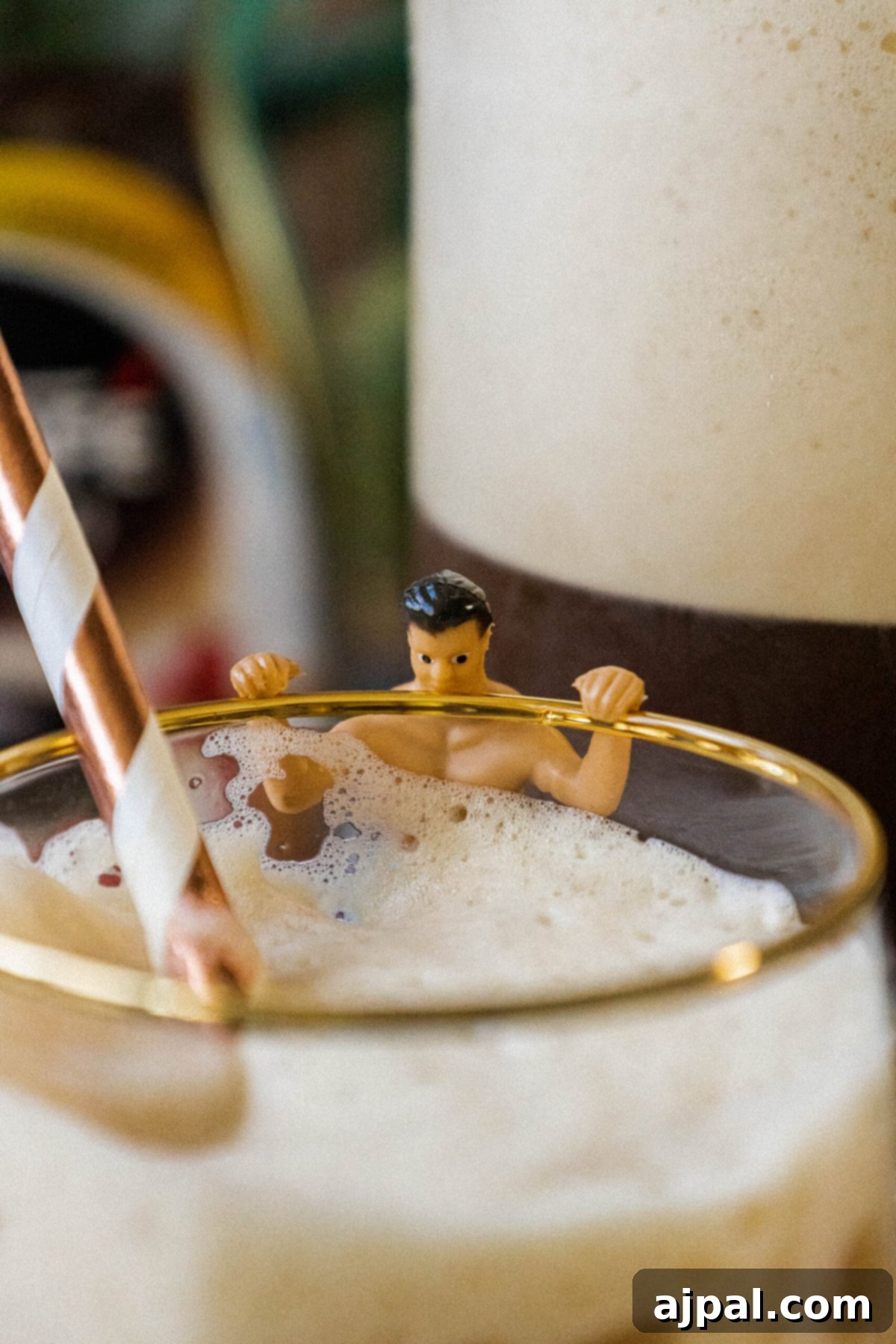 Plastic wine charm shaped like a man in a swimsuit on a glass of frappé coffee with a straw