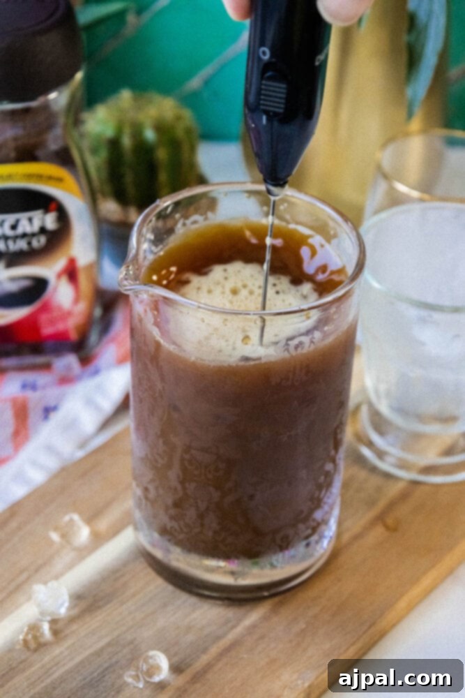 milk frother creating foam in frappé coffee