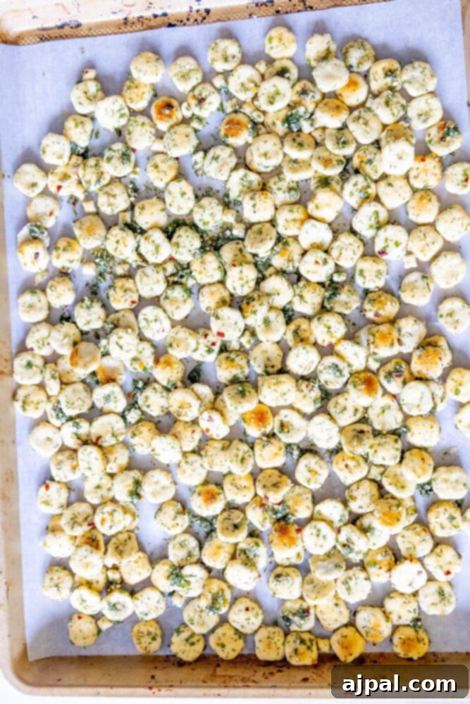 Kickin' Ranch Krunchies 8 oyster crackers with seasoning on a baking sheet with parchment paper