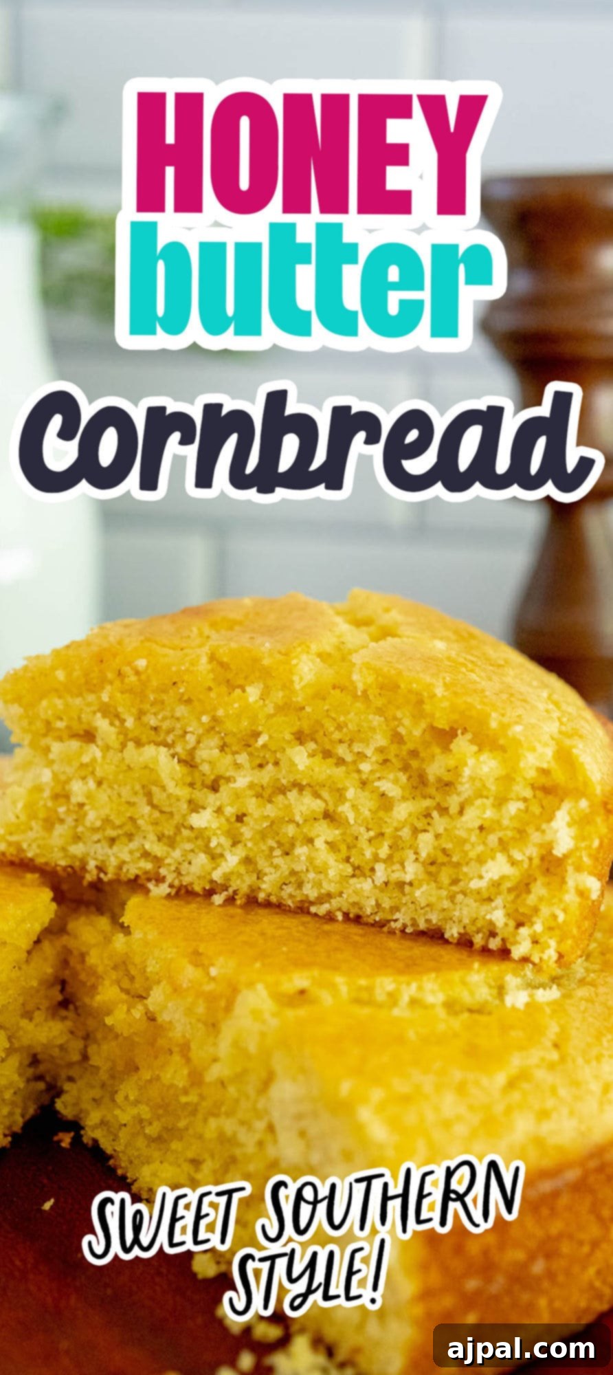 A wedge of golden honey butter cornbread perfectly sliced and placed on top of the main loaf of cornbread, sitting on a table.