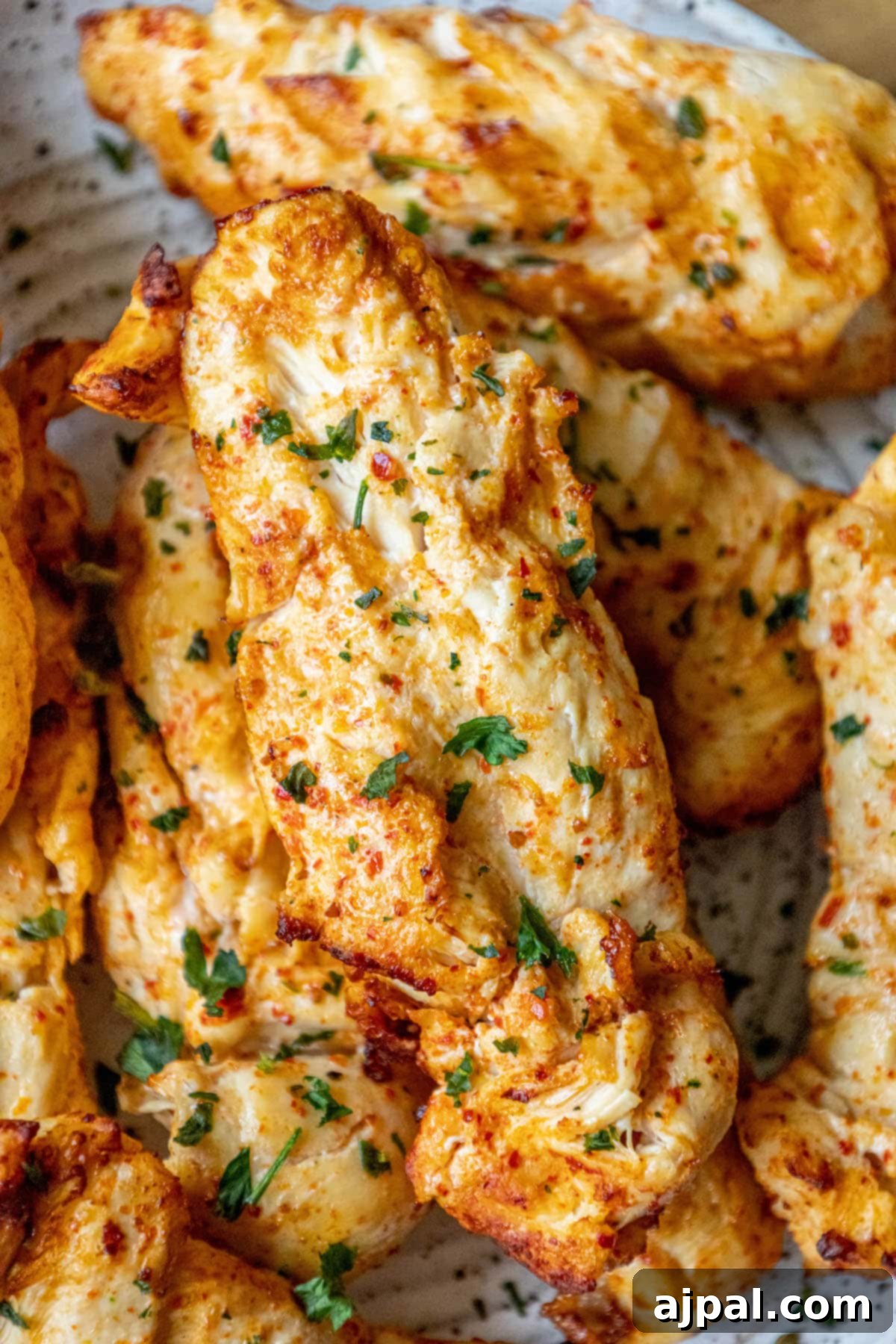Grilled chicken in Ajika seasoning on a white plate on a table with chopped cilantro on top, showcasing its rich, inviting colors.