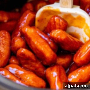 little smokies in bbq sauce in a crock pot with a spatula in the middle