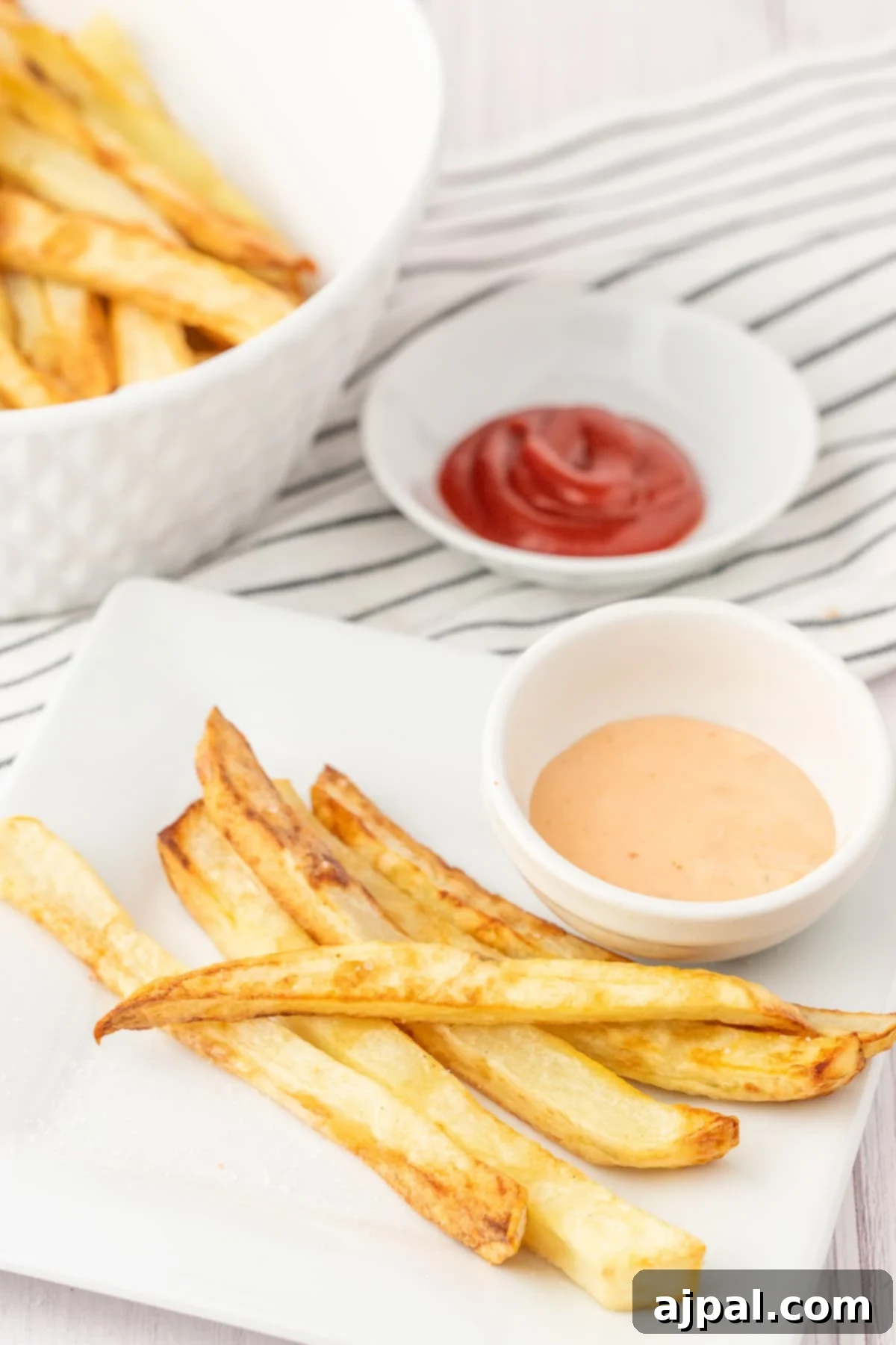 Ultimate Fry Dip 2 Crispy golden French fries on a white plate, served alongside a small cup of our signature creamy French fry sauce.